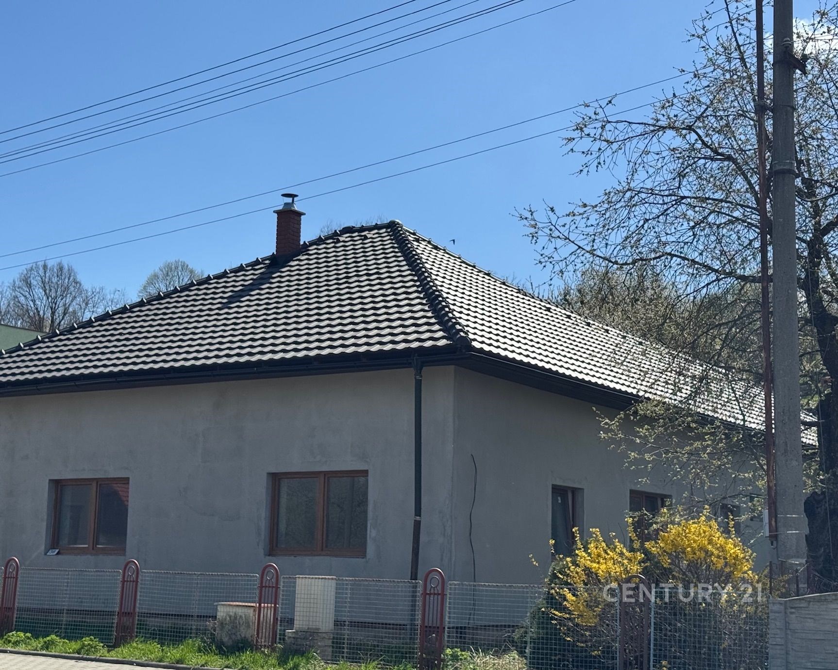 Rodinný dům s moderní střešní krytinou, obklopený zahradou, výrazná okna, tradiční venkovský styl, v klidné lokalitě.