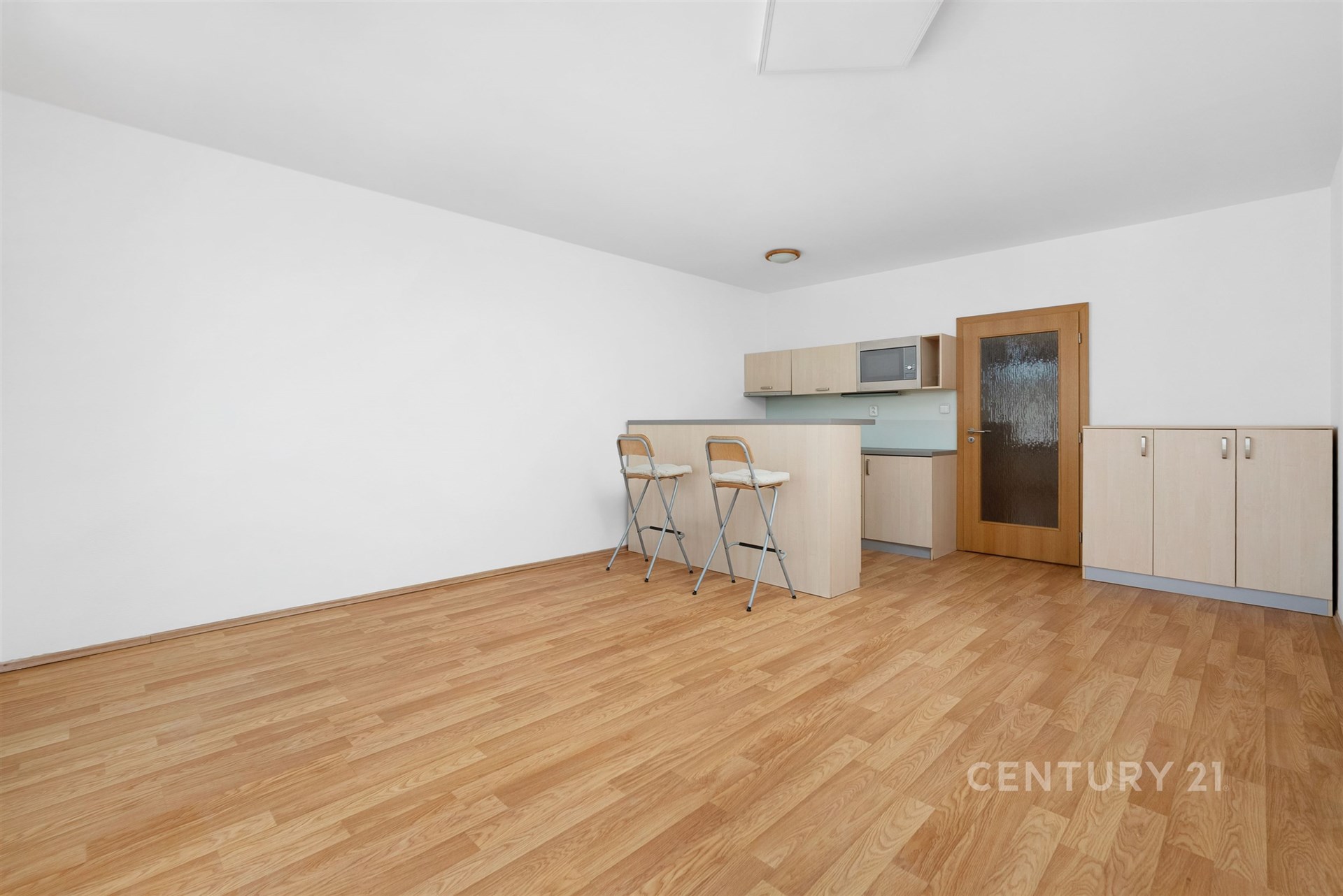 Kuchyňský kout s barovým pultem a parketovou podlahou nabízí moderní design s vestavěnou skříní a světlými dřevěnými skříňkami.