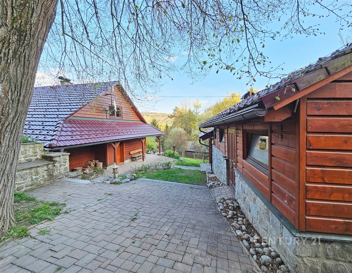 Tradiční dřevěná chalupa s pálenou střešní krytinou, kamennou dlažbou a klidným venkovním prostorem.