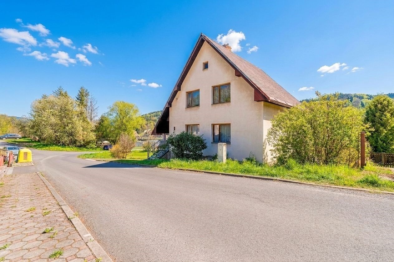 Rodinný dům s šikmou střechou, obklopený zelení, nacházející se na klidném místě. Dům má potenciál pro rekonstrukci.