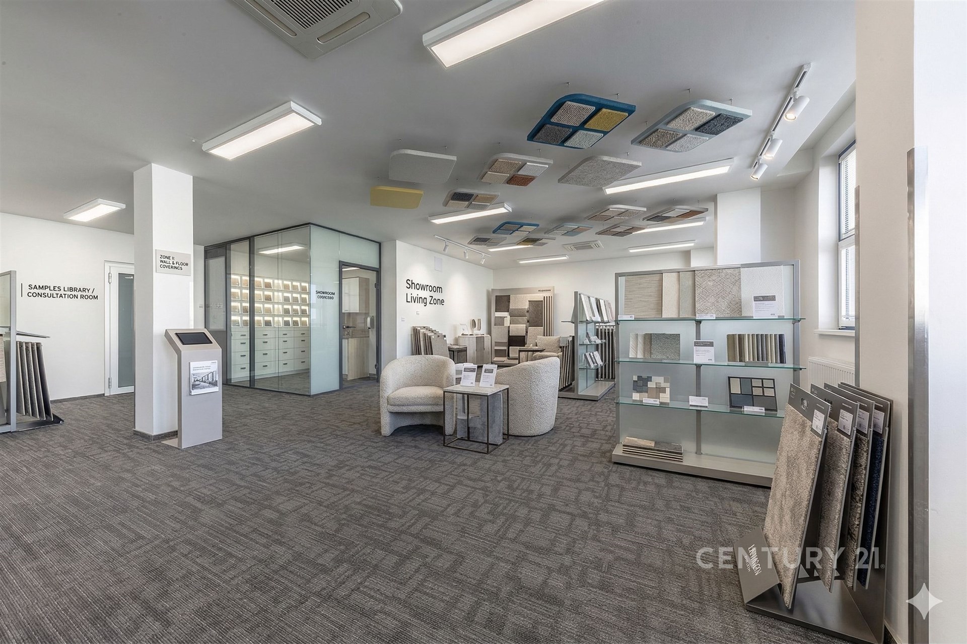 Pracovní showroom s moderním kobercem, velkým výběrem materiálů a vzorků, světlý interiér s velkými okny a skleněnými příčkami.