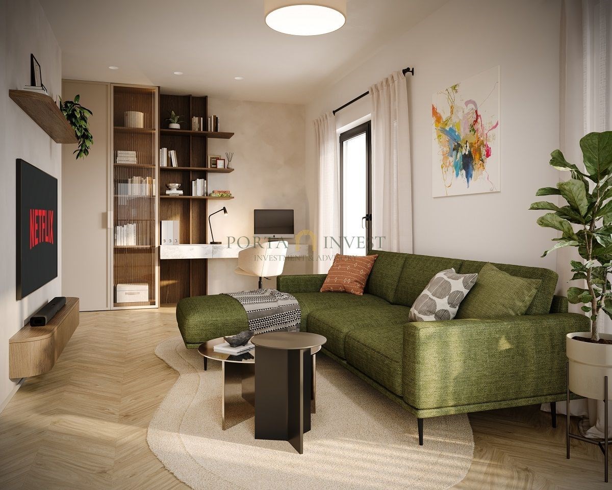 Světlý obývací pokoj s parketovou podlahou, moderní zelená pohovka a velká okna. Minimalistický design s pracovním koutem a knihovnou.