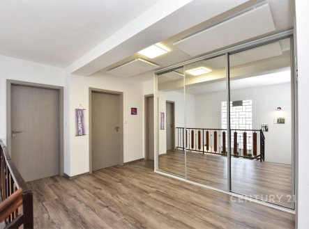 Chodba s laminátovou podlahou, vestavěné skříně a moderní design, světlý prostor díky velkým oknům a minimalistické osvětlení. | Prodej - dům/vila, 273 m²