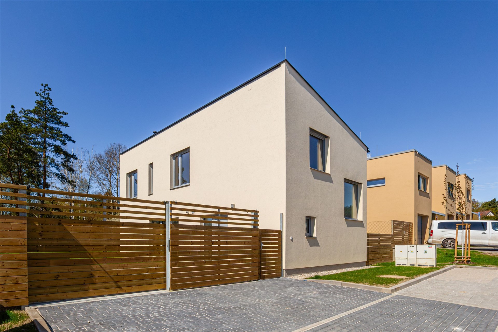 Moderní rodinný dům, dřevěný plot, zpevněná příjezdová cesta, novostavba, klidná rezidenční oblast