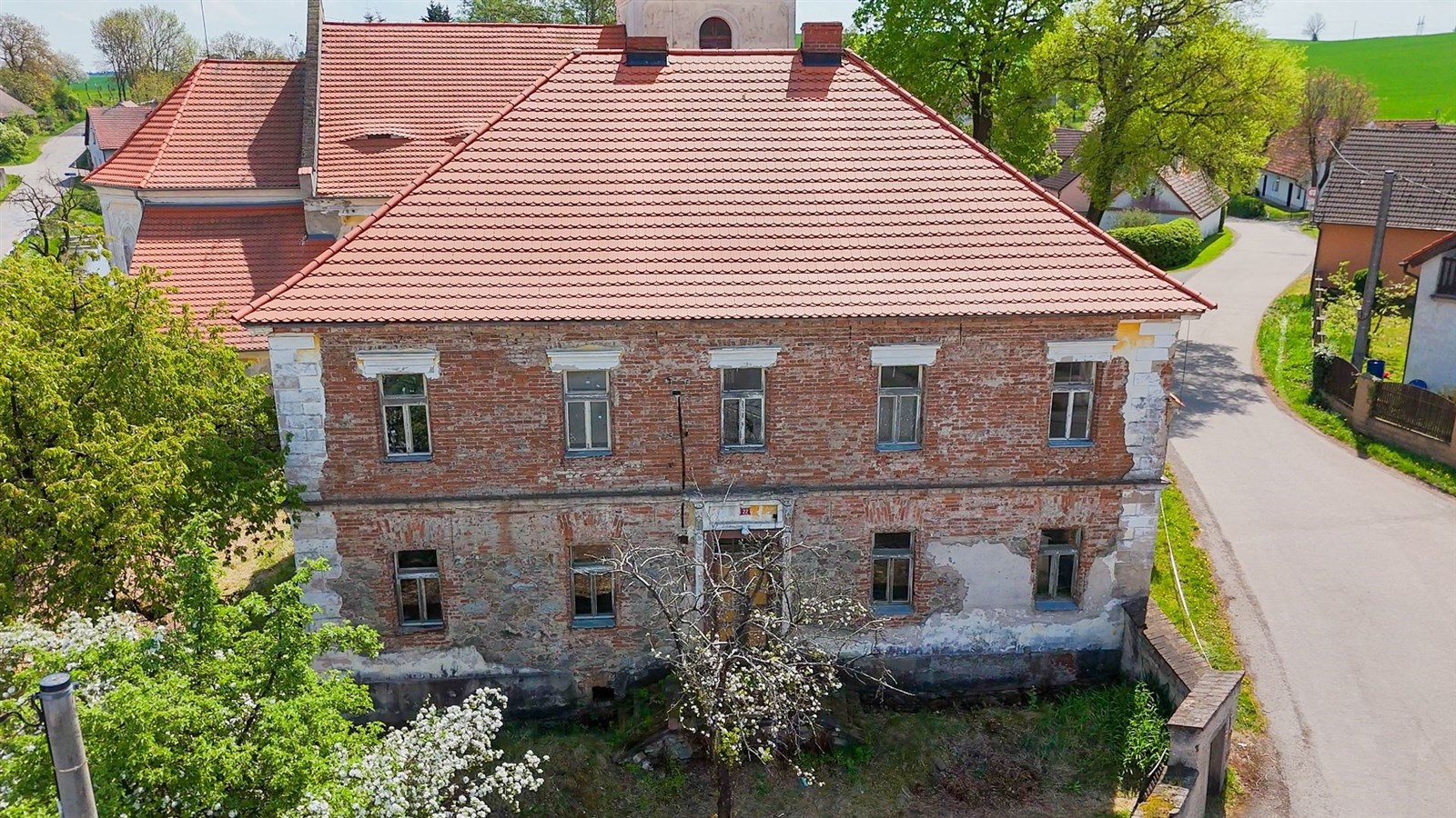 Historický dům s červenou střechou, cihlová fasáda, potřeba rekonstrukce, klidná lokalita s okolní zelení.
