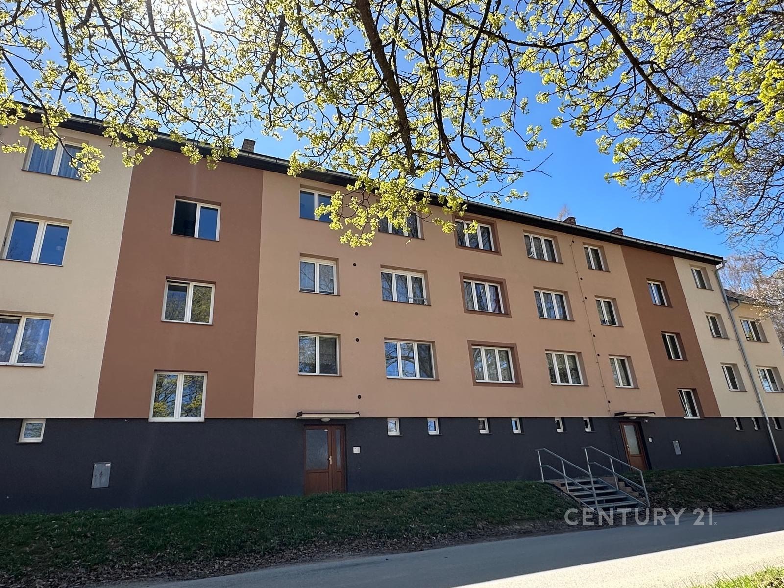 Exteriér bytového domu s novou fasádou, plastová okna, klidná lokalita, dobře udržovaný.