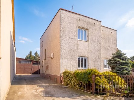 Exteriér rodinného domu s velkou příjezdovou cestou, betonová fasáda, moderní okna a udržovaná zahrada okolo plotu. | Prodej - dům/vila, 230 m²
