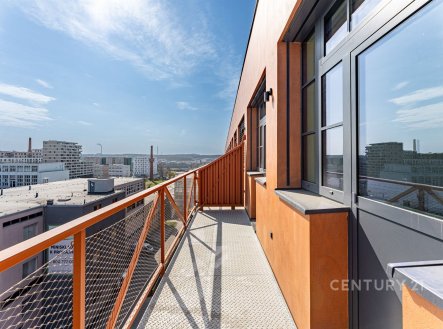Prostorný balkon s kovovým zábradlím, velká plastová okna, moderní design, s výhledem na městskou zástavbu a jasnou oblohu. | Prodej bytu, 2+kk, 48 m²