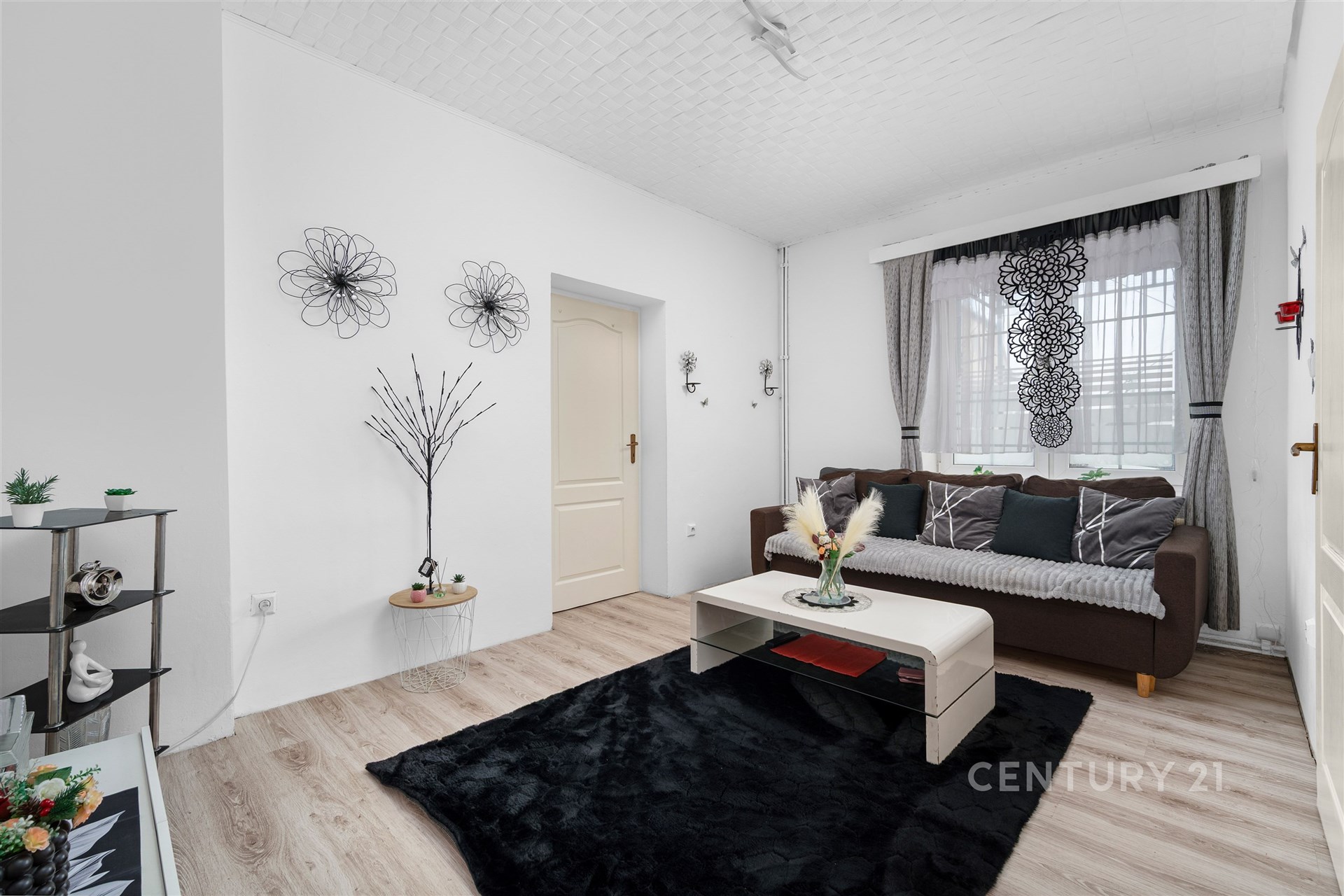 Světlý obývací pokoj s moderními prvky, laminátovou podlahou a velkými okny, které zajišťují dostatek přirozeného světla.