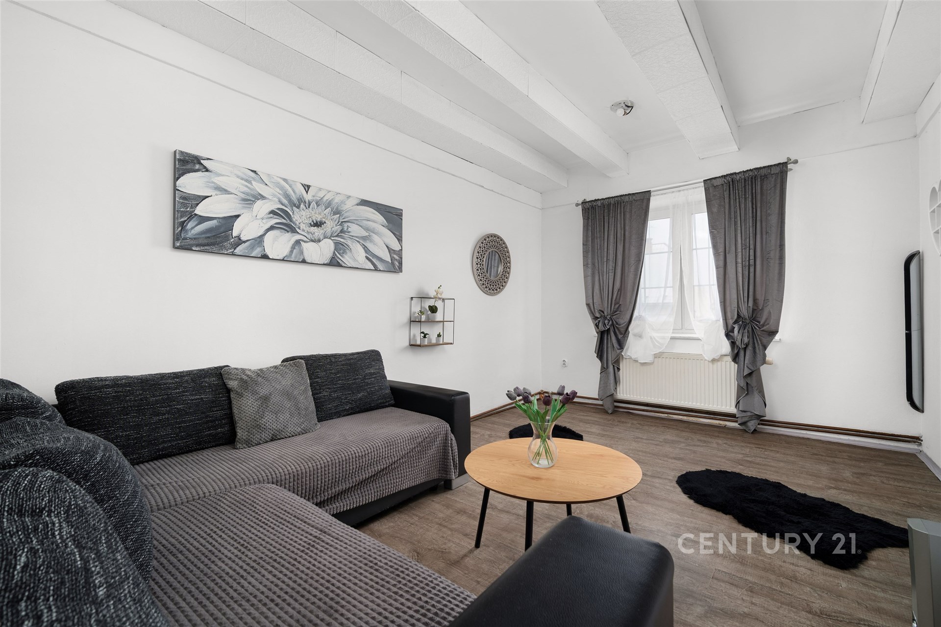 Světlý obývací pokoj s moderním designem, parketová podlaha, velká okna s elegantními závěsy, kvalitní nábytek, rekonstruovaný interiér.