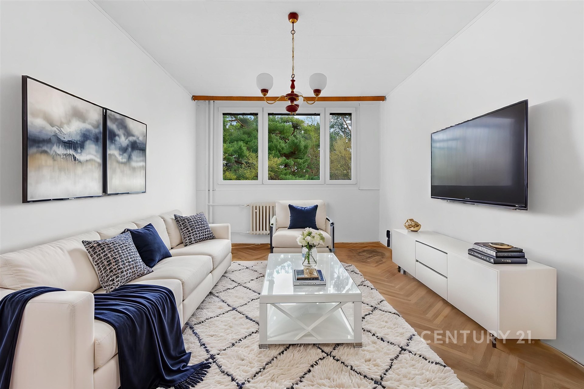 Světlý obývací pokoj s parketovou podlahou, velkými okny a moderním zařízením, nabízí útulný a elegantní prostor pro relaxaci.