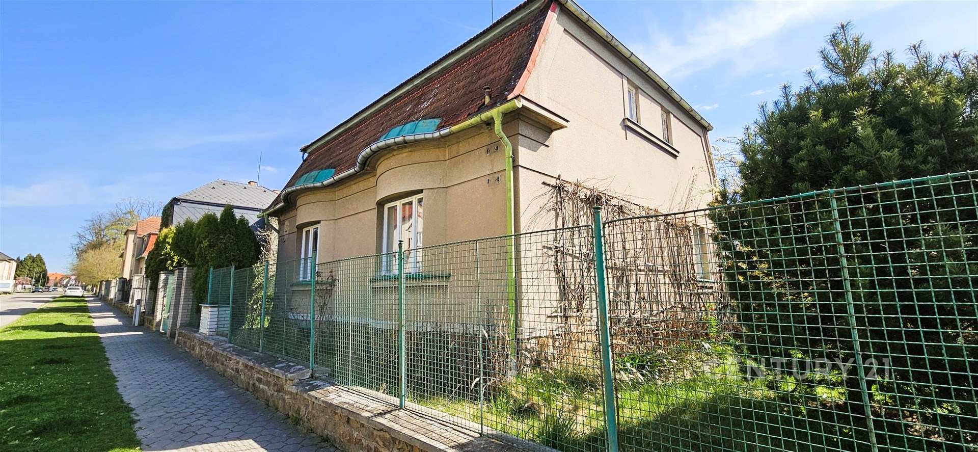 Exteriér rodinného domu se zahradou, nacházející se v klidné části města. Budova je zrekonstruovaná a obklopená zelení, ideální pro rodiny.