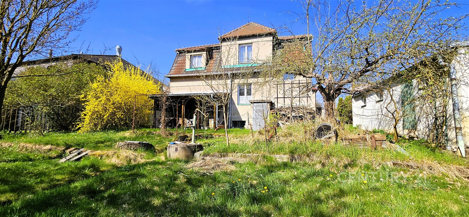Průčelí rodinného domu s rozlehlou zahradou, obklopenou vzrostlými stromy a keři, v klidném venkovském prostředí, čekající na rekonstrukci.
