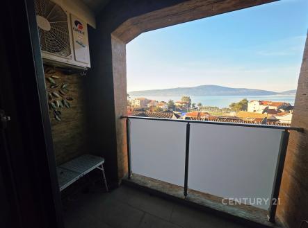 Úzký balkon s výhledem na moře, moderní dlažba a kovové zábradlí, ideální pro relaxaci i jako úložný prostor.