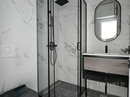 Moderní koupelna s mramorovými obklady, proskleným sprchovým koutem a elegantním zrcadlem, stylová a nadčasová úprava.