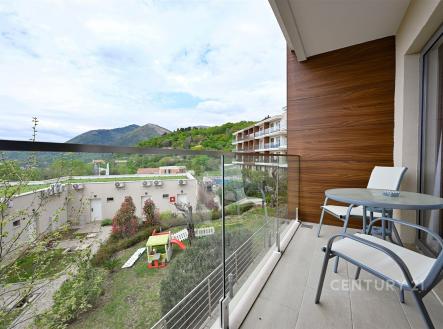 Balkon s moderní dlažbou a skleněným zábradlím, nabízí výhled na hory a okolní přírodu, ideální pro relaxaci a maximální využití plochy.