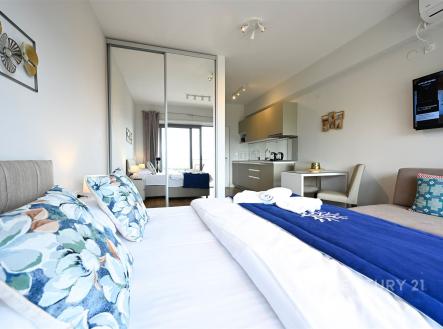 Prostorná ložnice s moderním designem, velkými okny a parketovou podlahou. Vestavěné skříně a světlé barvy dodávají místnosti elegantní vzhled.