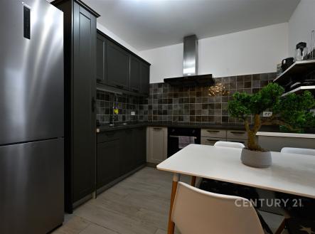 Moderní kuchyň s dlažbou, vestavěnými spotřebiči a tmavými skříňkami, nabízí elegantní a funkční prostor pro vaření a setkávání.