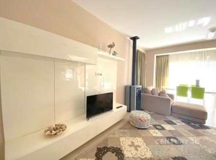 Světlý obývací pokoj nabízí moderní design, parketovou podlahu a velká okna pro dostatek přirozeného světla.