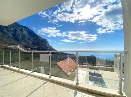 Prostorný balkon s dlažbou nabízí úchvatný výhled na hory a moře. Moderní skleněné zábradlí zajišťuje bezpečnost a otevřený pocit.