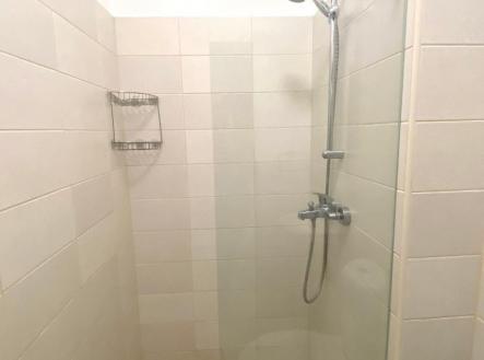 Prostorný sprchový kout s moderními dlaždicemi, skleněnou zástěnou a chromovou sprchovou hlavicí vytváří elegantní a praktický design.