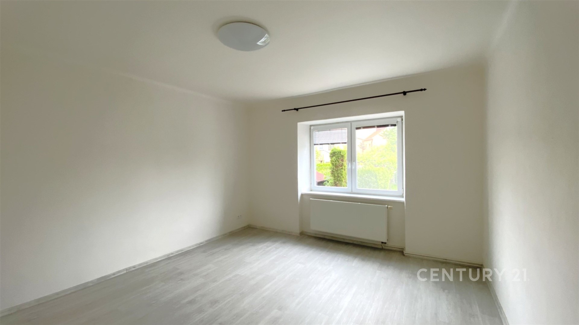 Světlá ložnice s moderními plastovými okny, světlou laminátovou podlahou a bílými stěnami, ideální pro přizpůsobení osobnímu stylu.