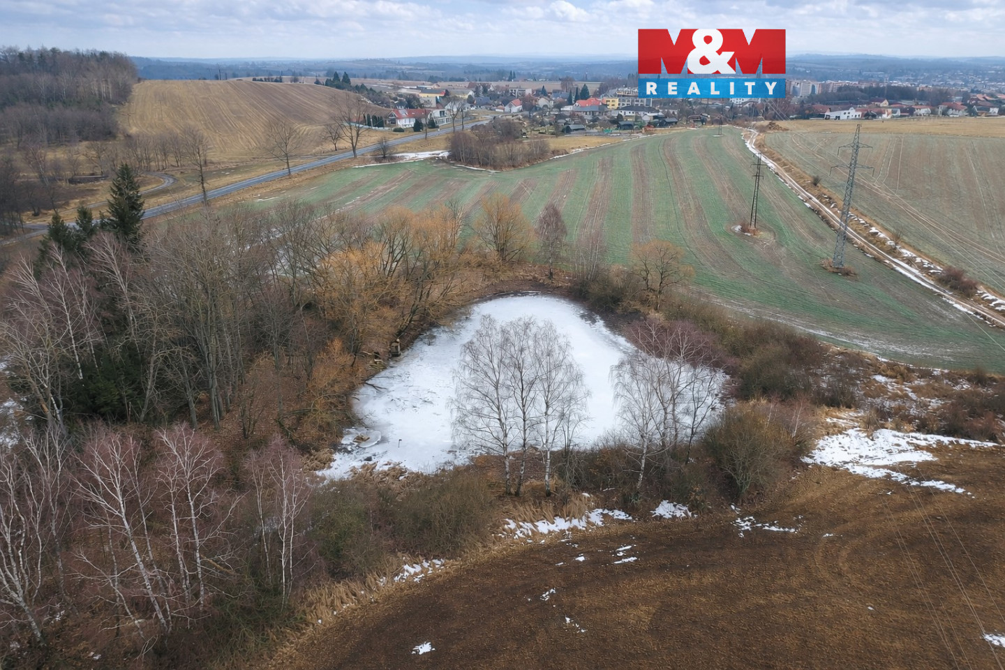 Zimní krajina s částečně zamrzlým rybníkem.jpg