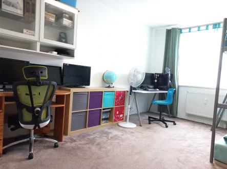 Domácí kancelář s kobercem, velkým oknem a moderním nábytkem. Včetně dvou pracovních stanic a úložných prostor, ideální pro práci z domova.