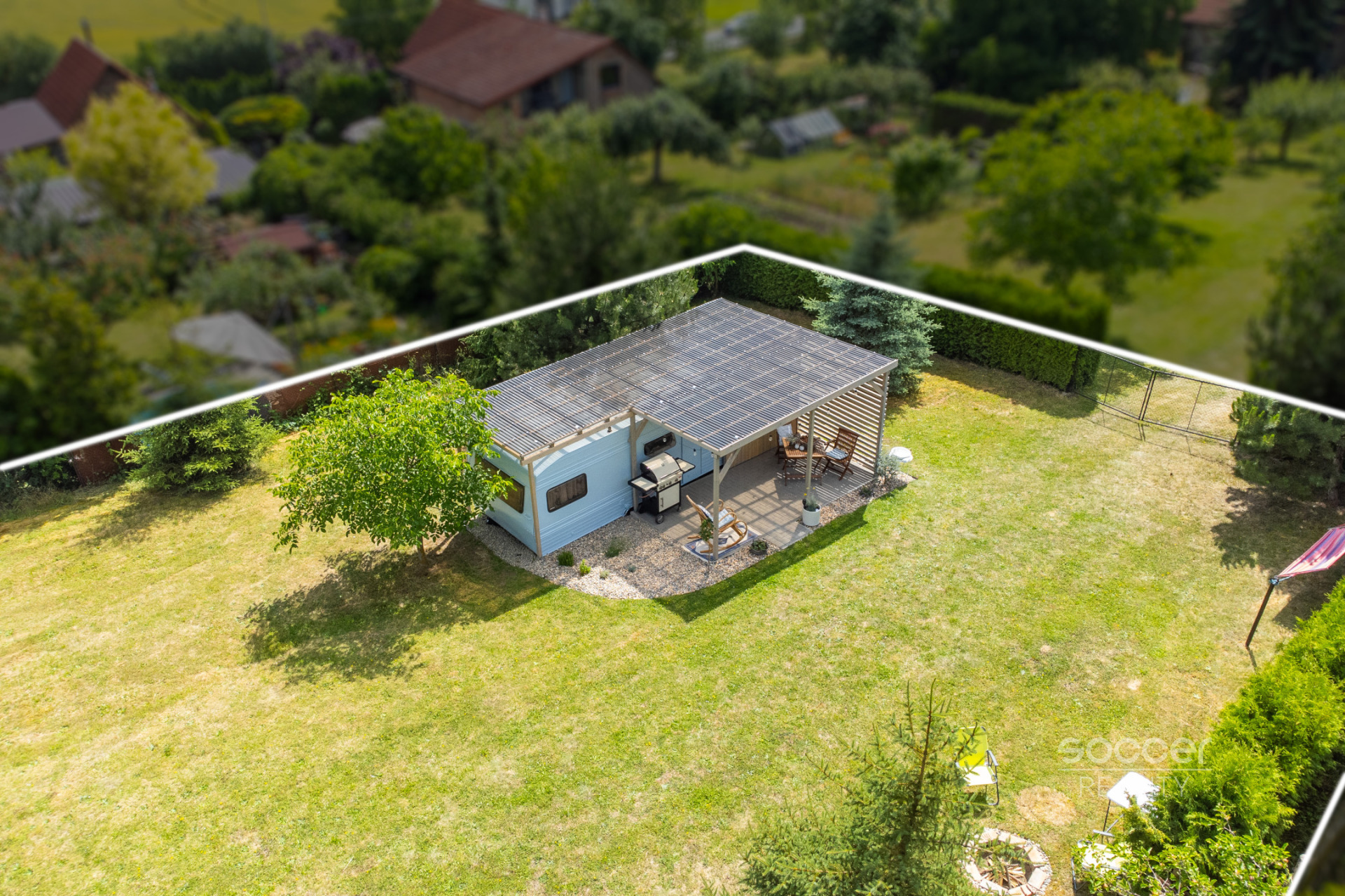 Příjemná venkovská zahrada s rekreačním karavanem a terasou.