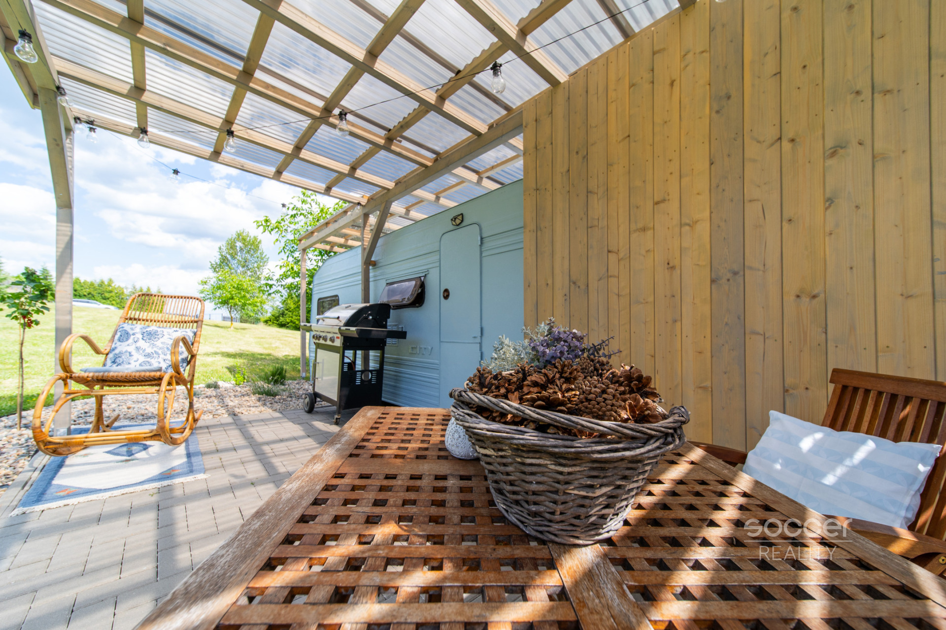 Příjemná venkovská zahrada s rekreačním karavanem a terasou.