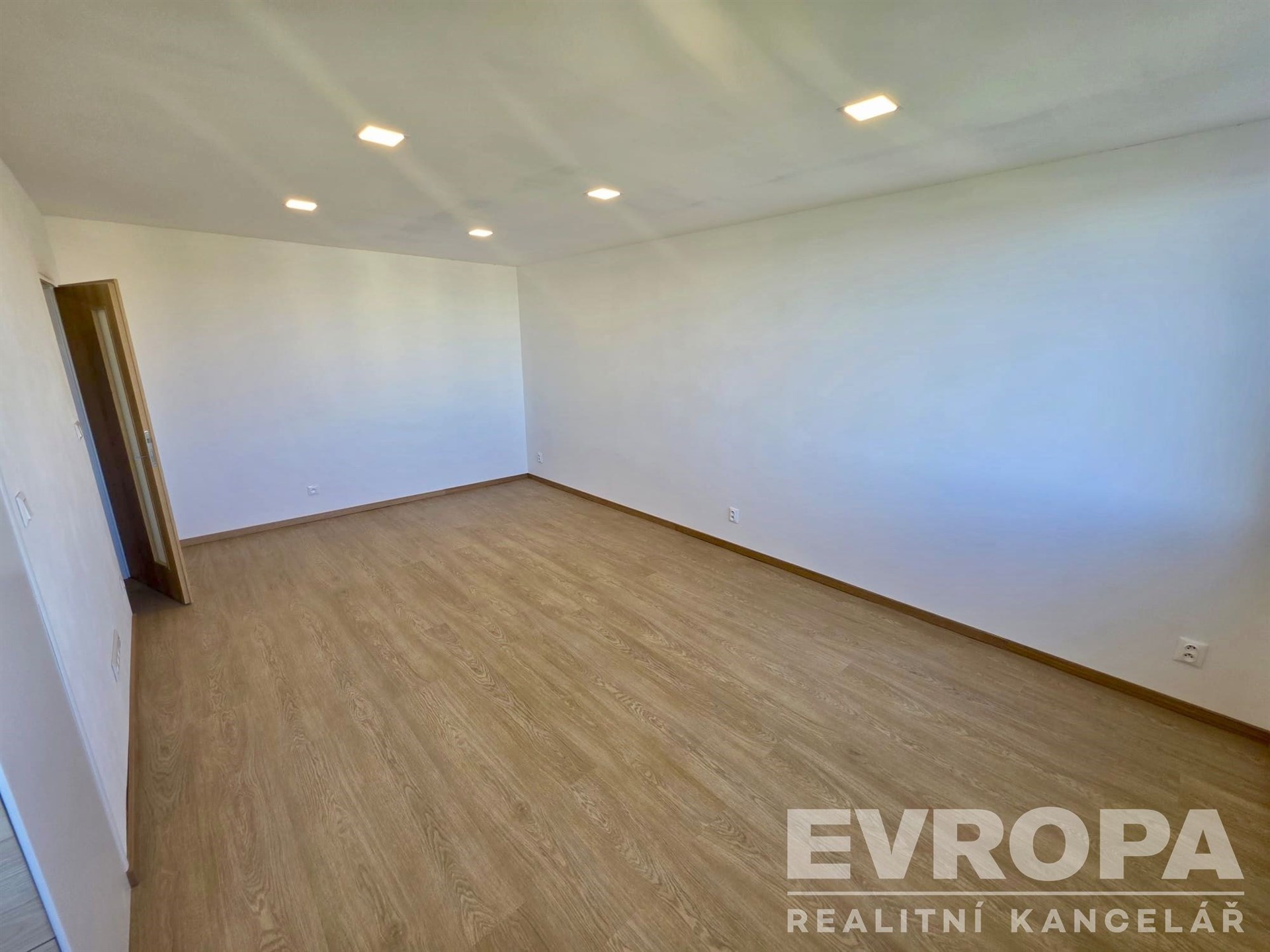 Prostorný obývací pokoj, parketová podlaha, moderní vestavěná světla, neutrální barvy stěn, ideální pro vlastní návrh interiéru
