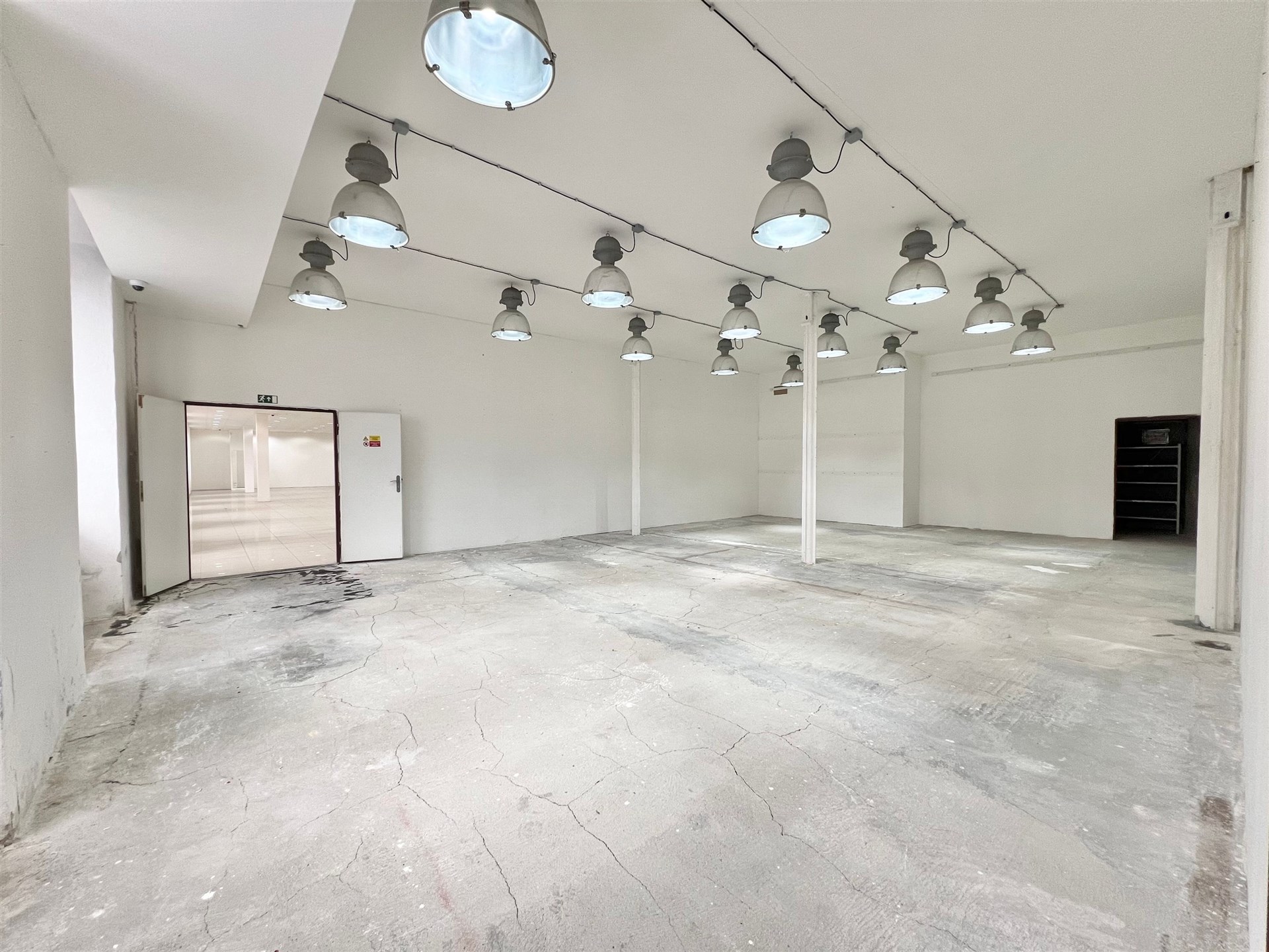 Prostorný průmyslový prostor, světlé stěny, betonová podlaha, vysoký strop, moderní osvětlení, vhodný pro skladování nebo výrobu
