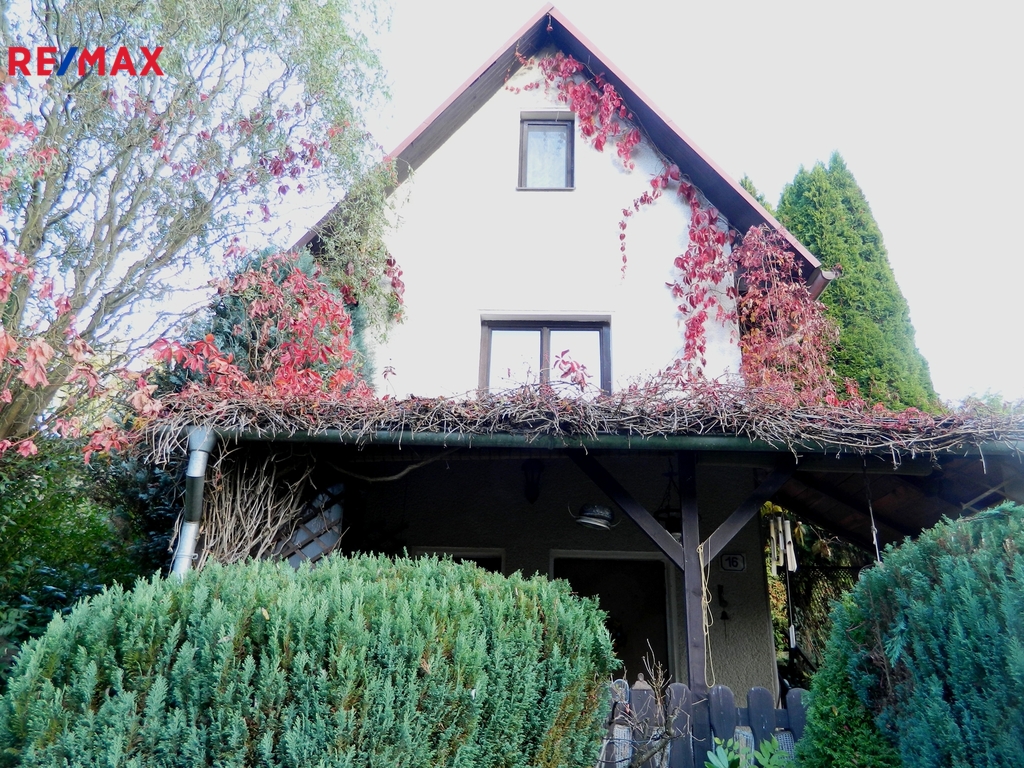 Průčelí chaty s pergolou.