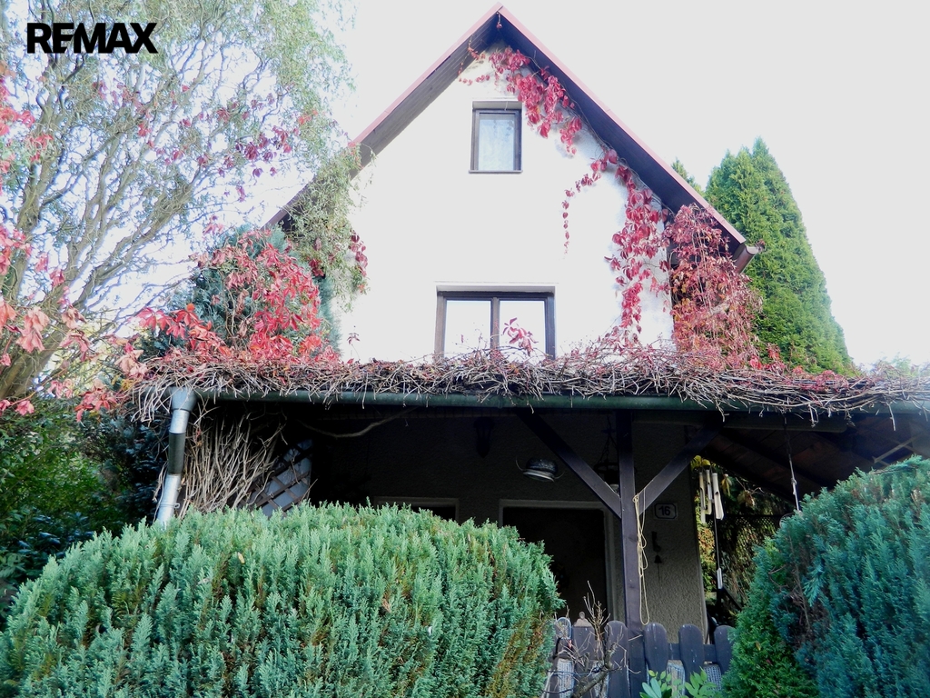 Průčelí chaty s pergolou.