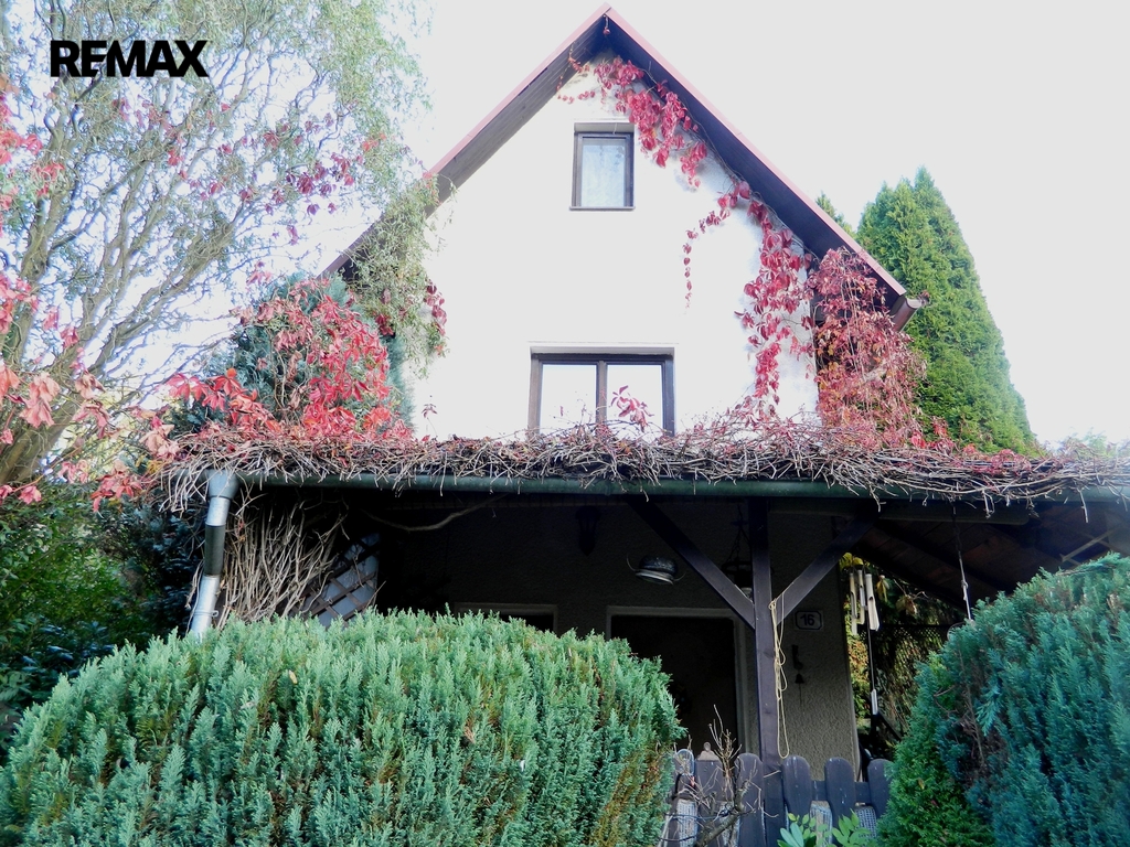 Průčelí chaty s pergolou.