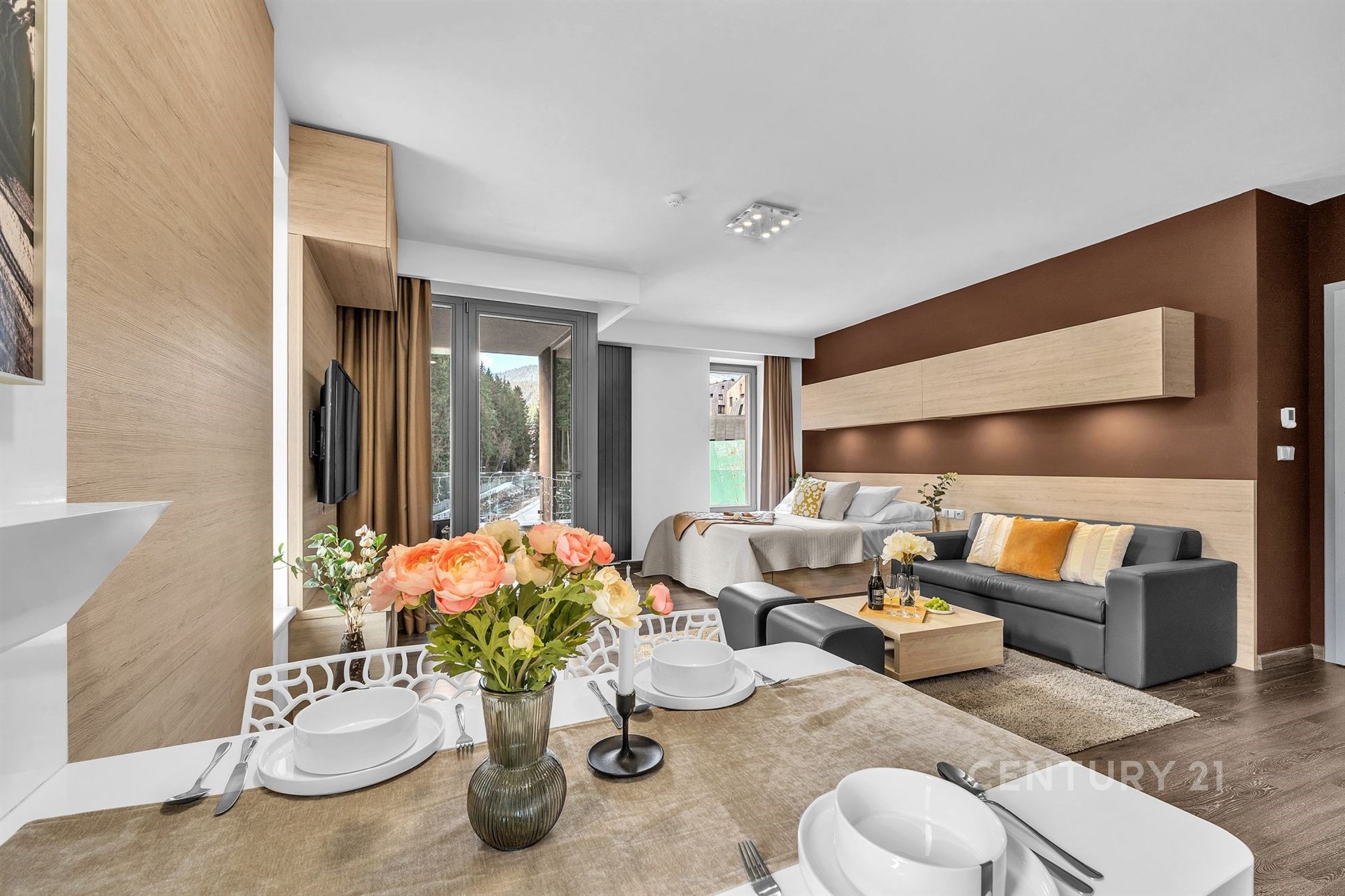 Moderní obývací pokoj s dřevěnými prvky, velkými okny a parketovou podlahou, která zajišťuje světlost a prostornost prostoru