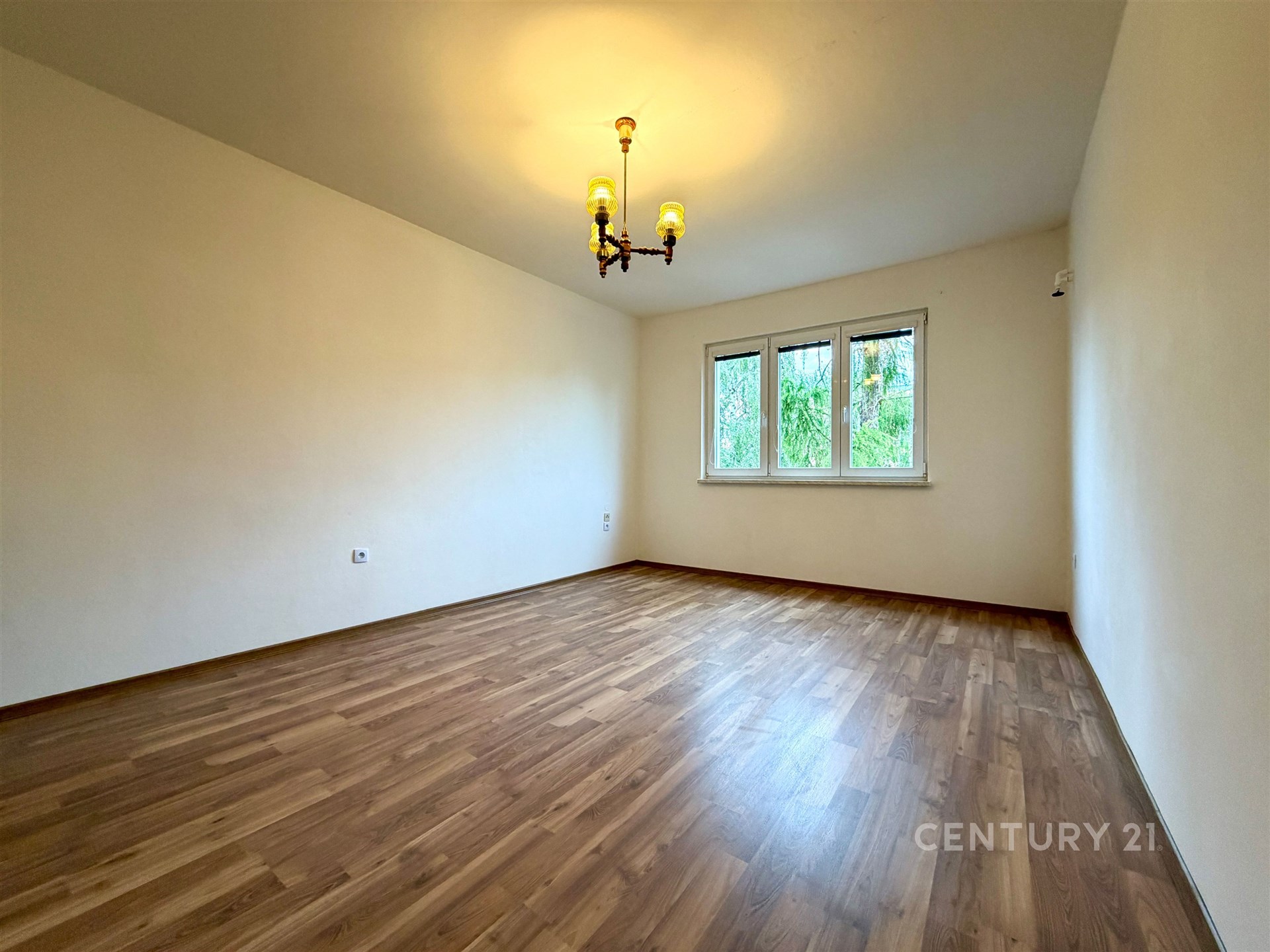 Prostorný obývací pokoj, parketová podlaha, velká okna, moderní styl, světlé prostředí, ideální pro rodinné bydlení.