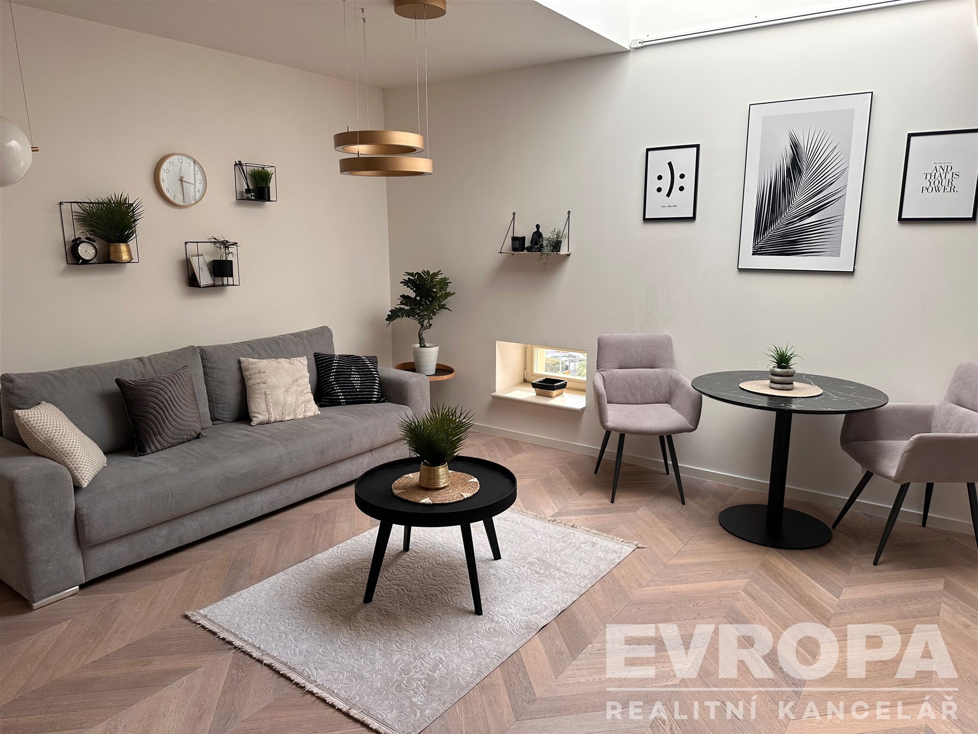 Světlý obývací pokoj se parketovou podlahou, velká okna, moderní nábytek, stylové dekorace, pohodlná sedací souprava a jídelní kout.
