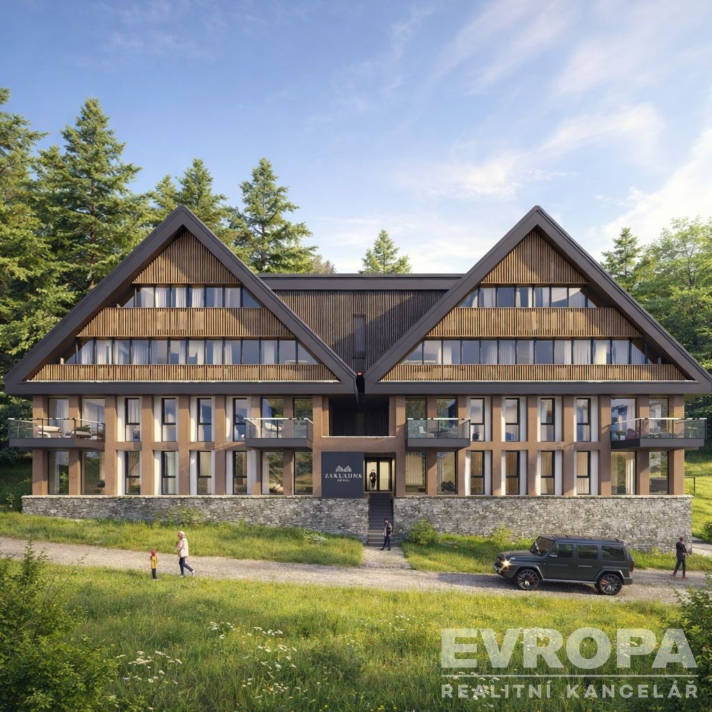 Horská chata s moderní architekturou, kamenný obklad, velká okna a balkóny, zasazená v malebné přírodě s lesy v pozadí