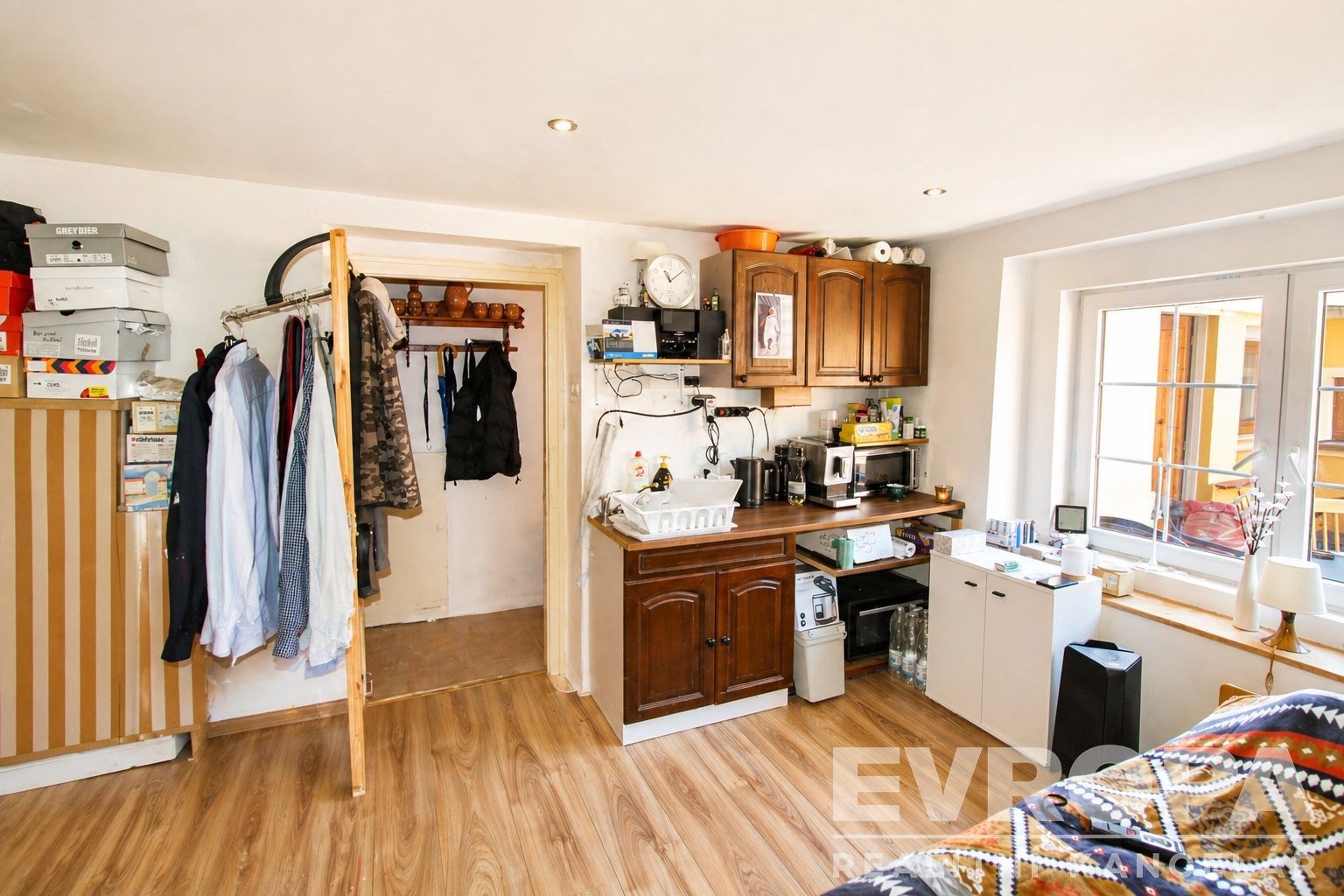 Studio s parketovou podlahou, vestavěnými skříněmi a moderní kuchyňskou linkou. Prostor působí světlým a útulným dojmem.