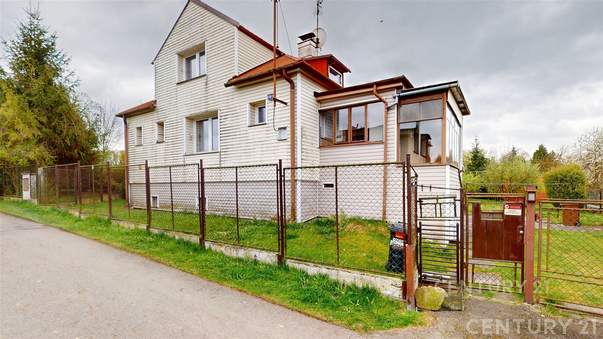 Dvoupatrový rodinný dům s bílým obkladem a červenou střechou, oplocená zahrada, prostorná veranda, klidná lokalita, dobrý stav.