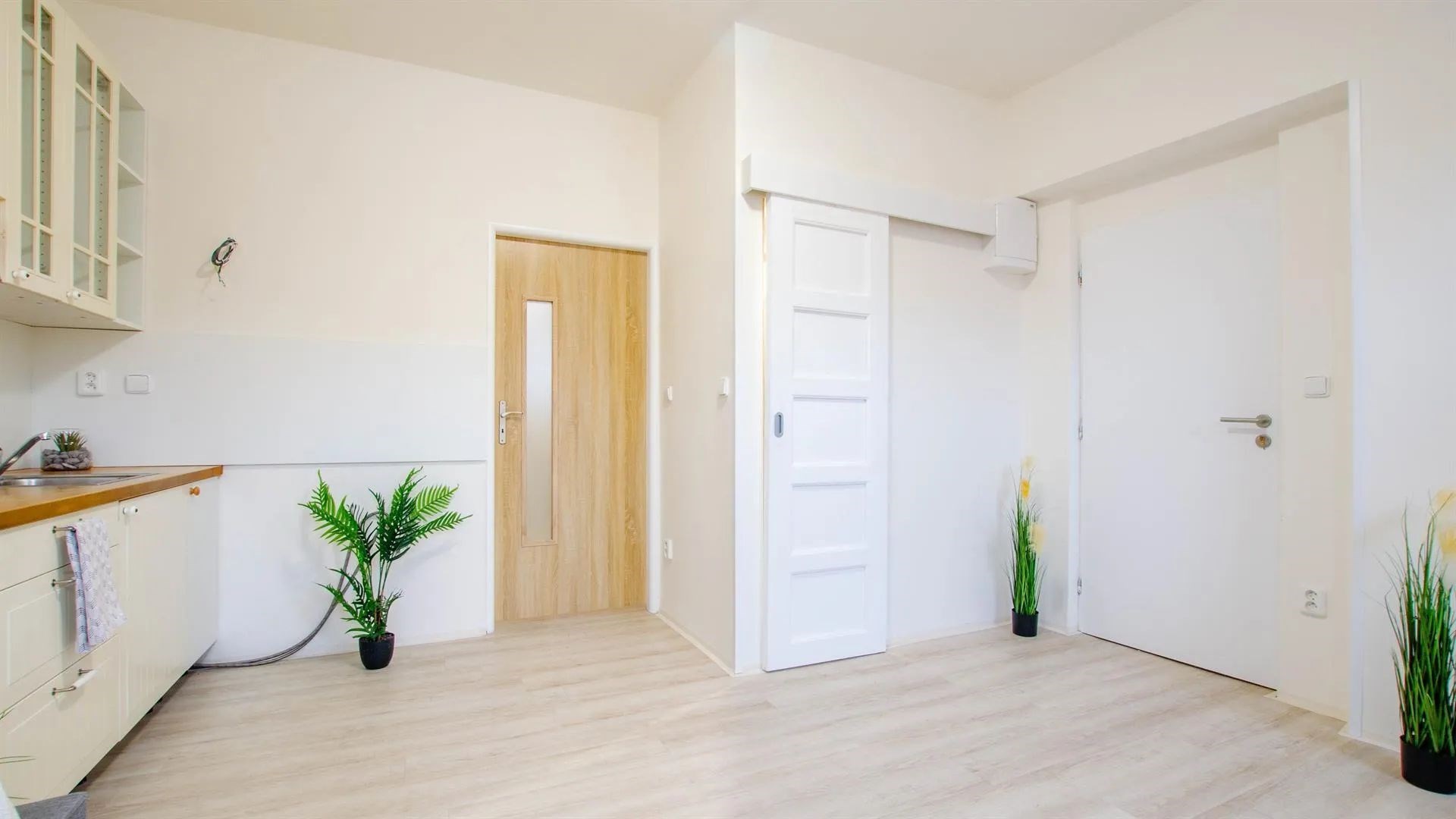 interiér prostor s skleněné vložky, dřevěná podlaha, bílé skříně, a dřez