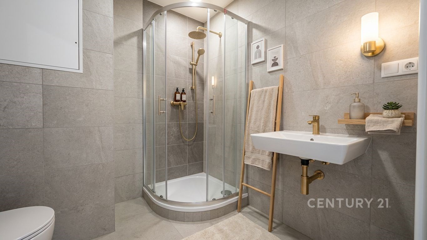 Koupelna s moderní sprchou, dlažbou a zlatými doplňky, laděná v neutrálních tónech, elegantně osvětlená s minimalistickým designem.