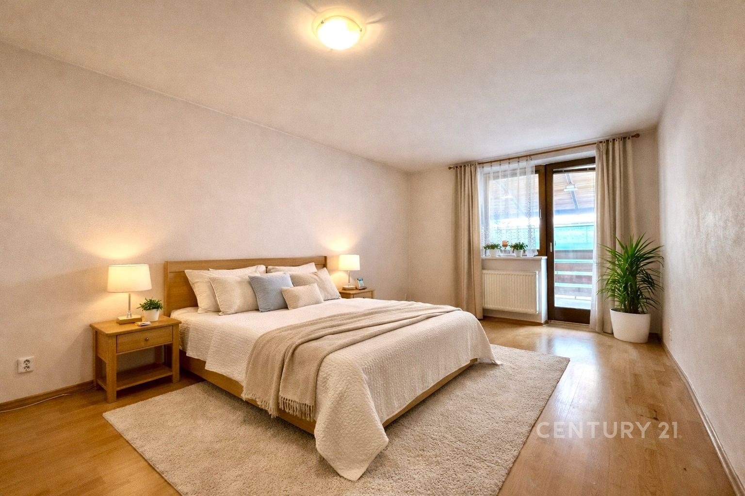 Prostorná ložnice s parketovou podlahou, velkými okny a moderním nábytkem, světlé stěny vytvářejí útulný prostor ideální pro relaxaci.