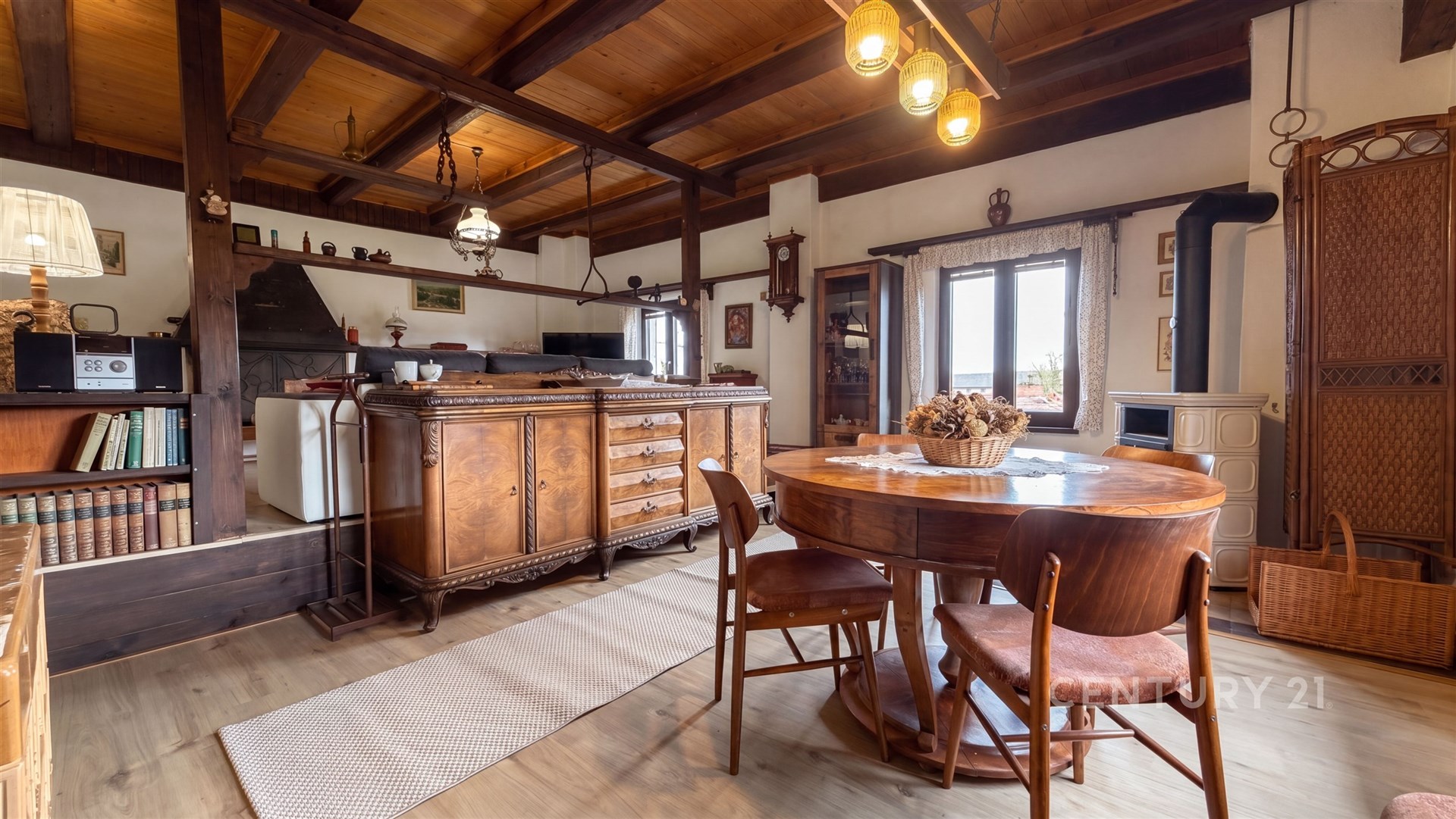 Rustikální obývací pokoj s dřevěným stropem, parketovou podlahou a krbovými kamny vytváří útulnou atmosféru pro relaxaci.