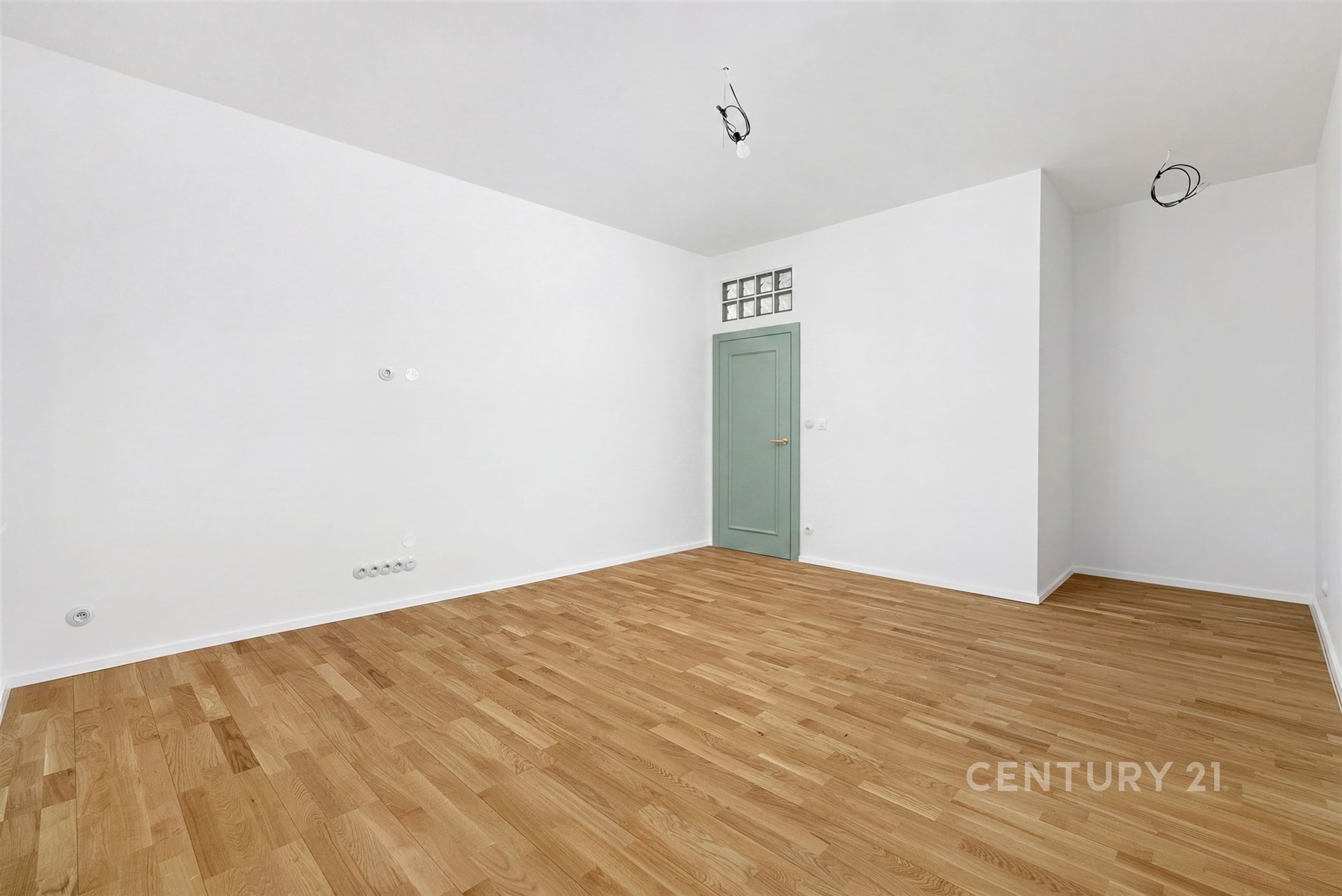 Prázdný obývací pokoj s parketovou podlahou, bílými stěnami a pastelovými dveřmi, minimalistický design, připravený k okamžitému nastěhování.