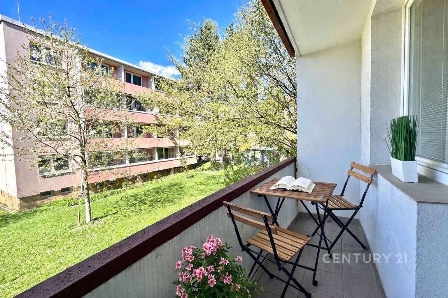 Zasklený balkon s výhledem na zeleň, dlažba a moderní terasa, ideální pro relaxaci a venkovní posezení