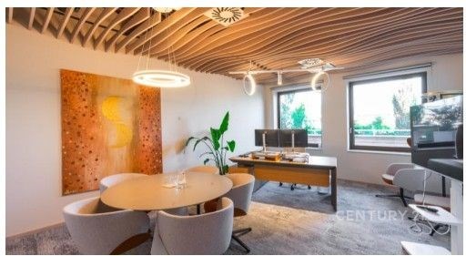 Moderní kancelář s velkými okny, parketová podlaha, designový nábytek, světlé osvětlení, elegantní prostředí vhodné pro pracovní prostředí.