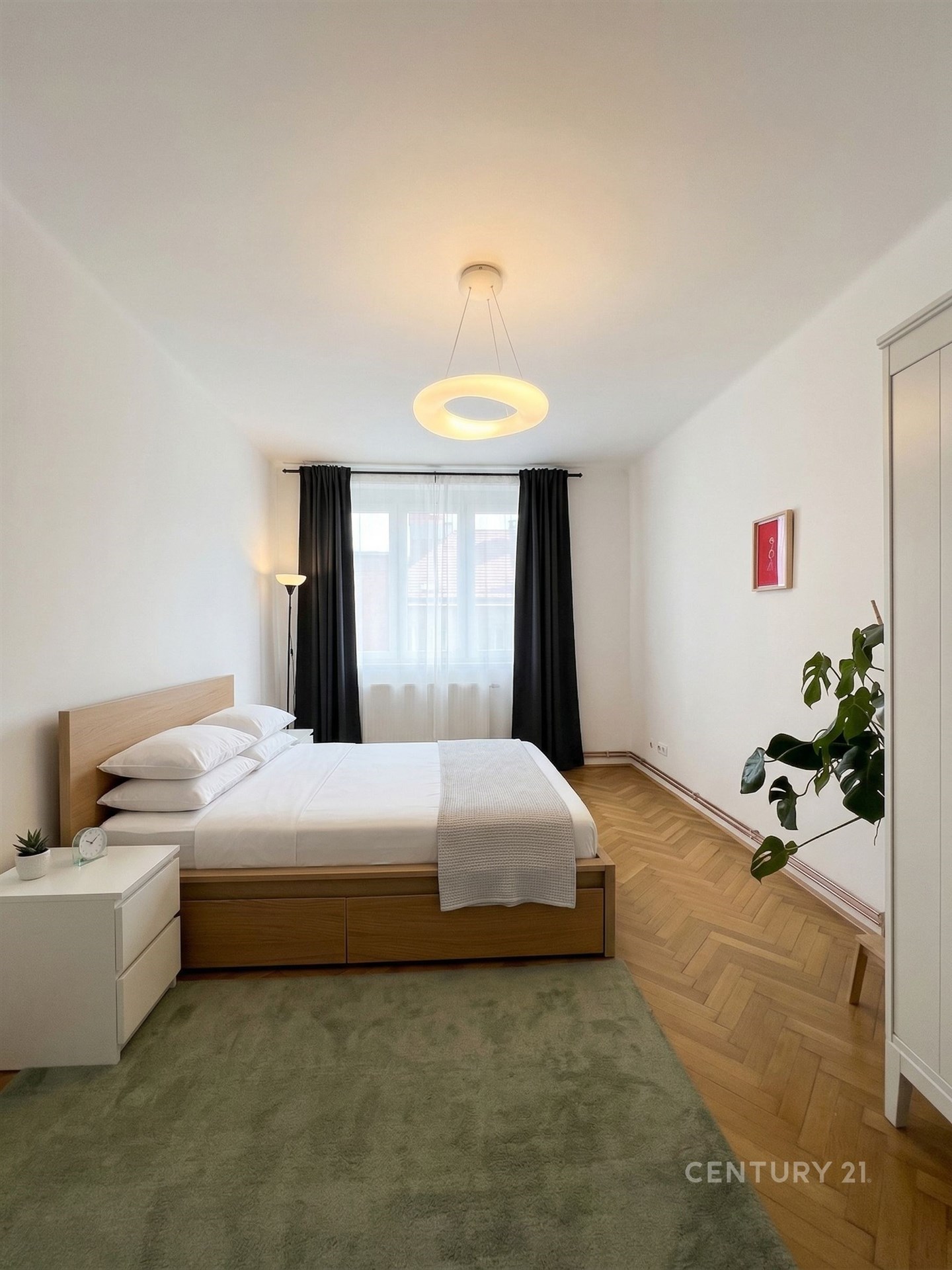 Prostorná ložnice s parketovou podlahou, velkým oknem.