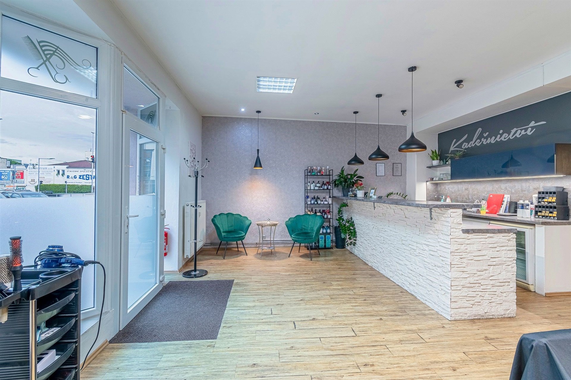 Moderní kadeřnický salon s dřevěnou podlahou, stylovým osvětlením a světlými zdmi, ideální pro klienty hledající kvalitní péči v elegantním prostředí.